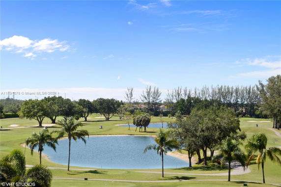 Panoramic view of a landscape with trees and a pond in a park-like setting.