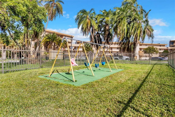 Outdoor playground with swingset near a residential building.