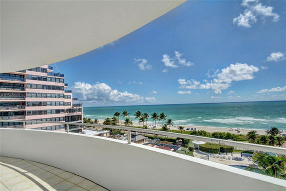 Panoramic view of a beach and ocean seen from a building balcony.