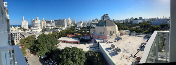 Wide-angle view of city buildings including a domed structure with surrounding greenery and other high-rise buildings.