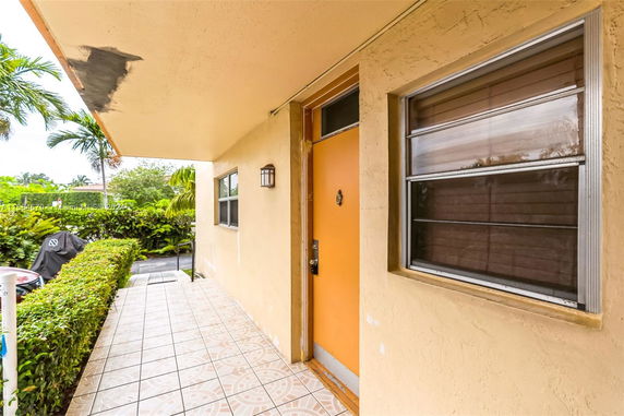 Front view of a house entrance with a yellow door and tiled pathway.