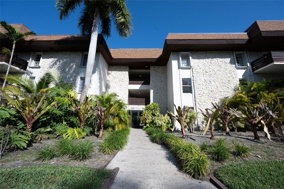 Front view of a multi-story building with stone facade and brown roof.