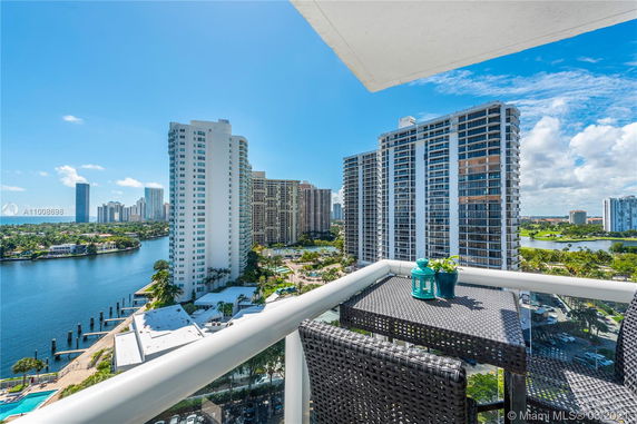 View of high-rise buildings from a balcony with a table and chairs.