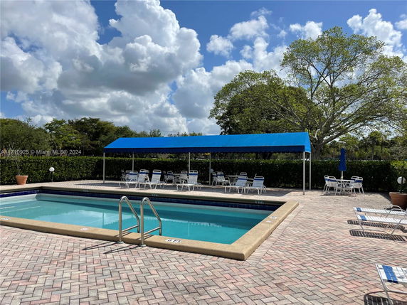 Outdoor swimming pool with a surrounding patio area and shaded seating.