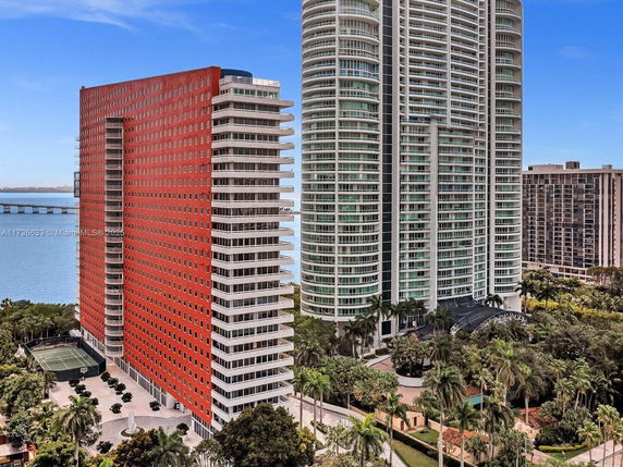View of high-rise buildings near the waterfront with tennis courts visible.