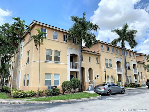Front view of a multi-story apartment building with arched entrances and balconies.