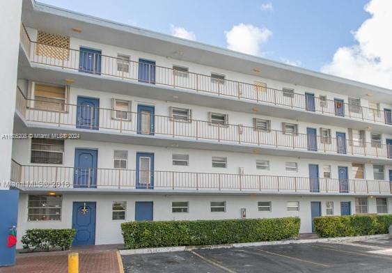 Front view of a multi-story residential building with balconies and blue doors.