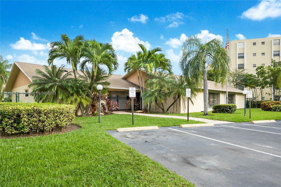 Front view of a single-story house with a sloped roof and palm trees in the yard.