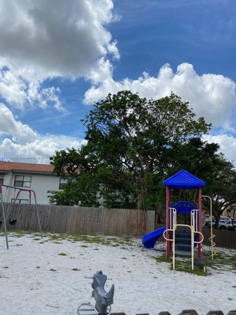 Playground with slides and swings surrounded by a fence.