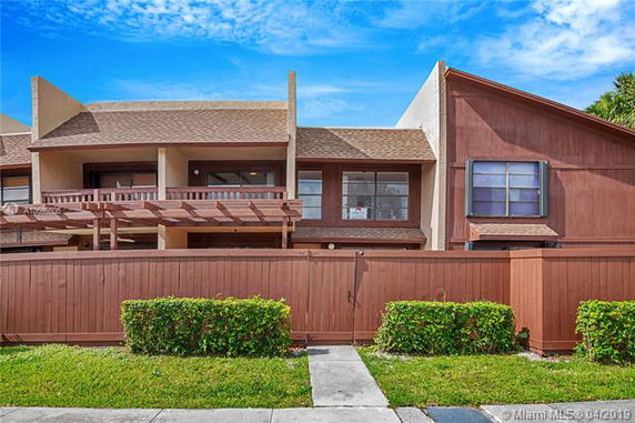 Front view of a two-story house with a wooden fence and pergola.