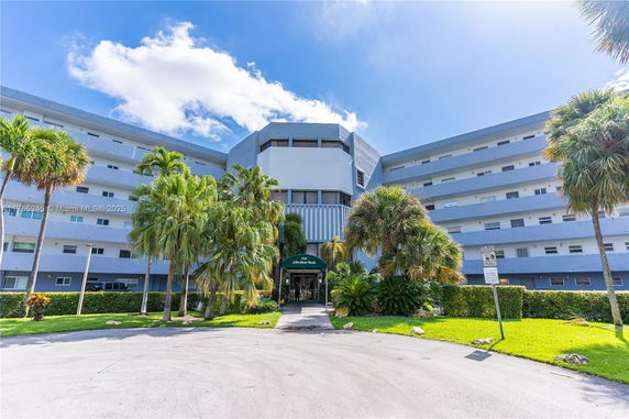 Front view of a multi-story building with balconies and palm trees.