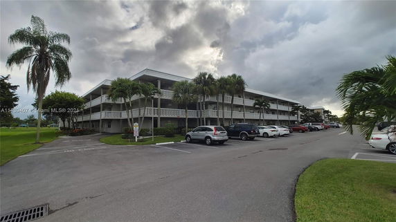 Front view of a multi-story building with a parking area in front.