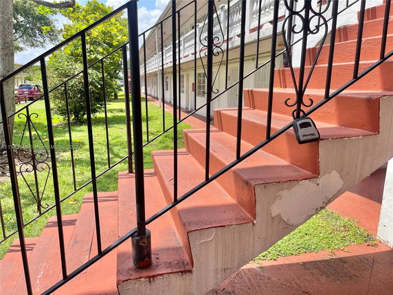 Staircase leading to an upper level of a building with visible railings and a lockbox.