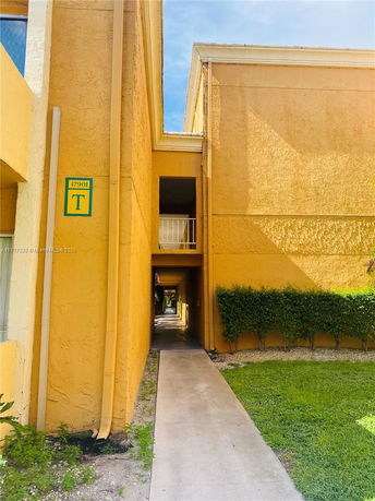 Front view of a multi-story building with a yellow exterior and walkway.