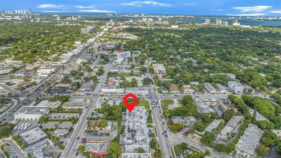 Aerial panoramic view of a city showing buildings, roads, and greenery.