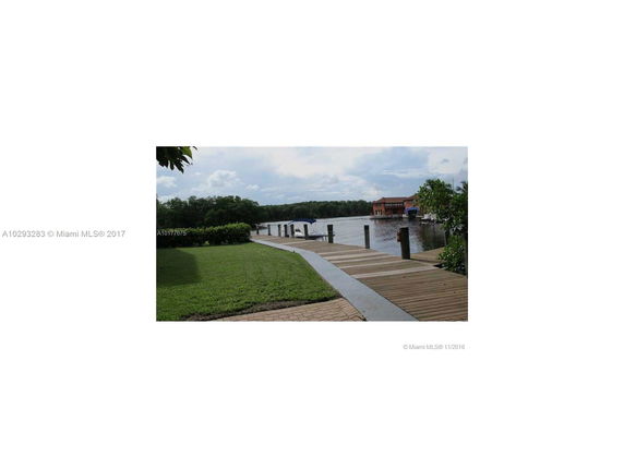 View of a waterfront area with a wooden dock and lush greenery.