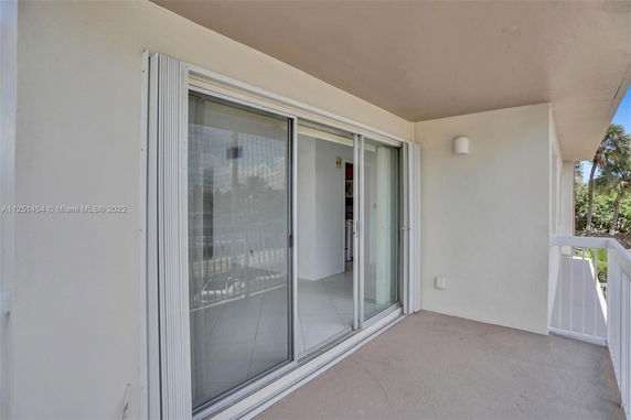 View of a small outdoor balcony with sliding glass doors and a white railing.