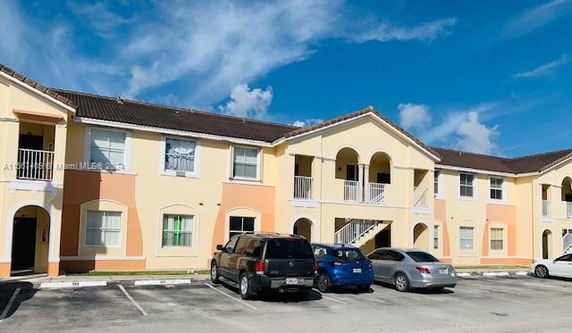 Front view of a two-story apartment building with multiple entrances and a parking area.