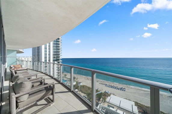View from a balcony overlooking the ocean with nearby high-rise buildings.