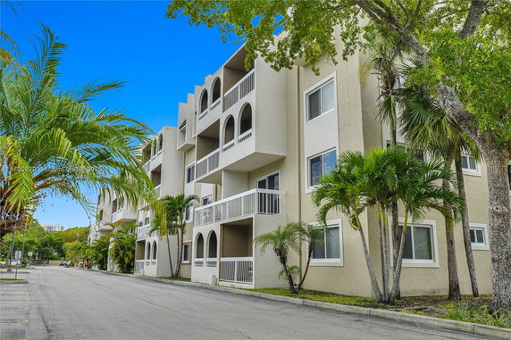 Front view of a multi-story apartment building with balconies and arched openings.