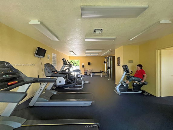 Indoor gym area with exercise machines and a person working out.