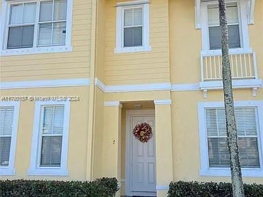Front view of a two-story yellow house with white trim and a central front door.