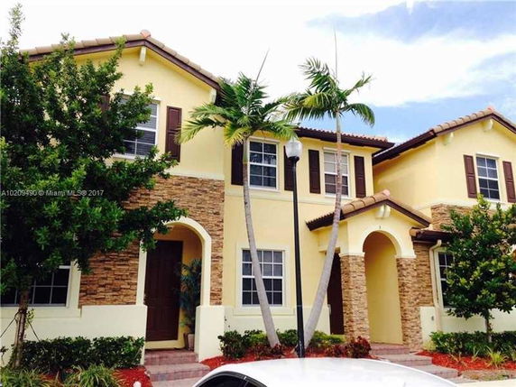 Front view of a two-story house with a tan and stone exterior.
