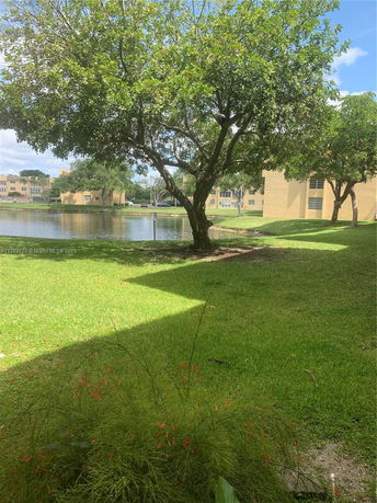 Buildings with a view of trees and a pond in the foreground.
