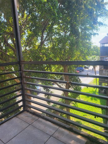 Balcony view of surrounding trees and parking area.