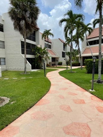 Front view of a multi-story apartment building with a tiled pathway.