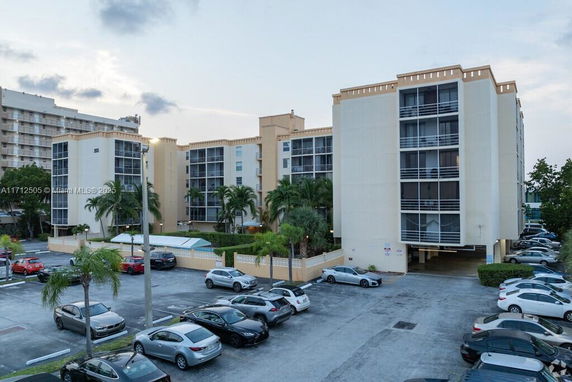 Front view of a multi-story residential building with balconies and parking area.