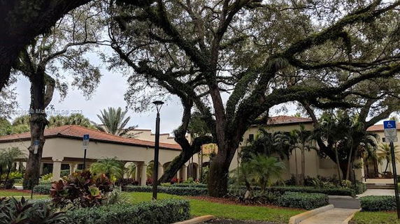 Front view of a building with an archway entrance and surrounding trees.