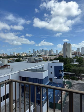 Panoramic view of a cityscape with buildings under a blue sky filled with clouds.