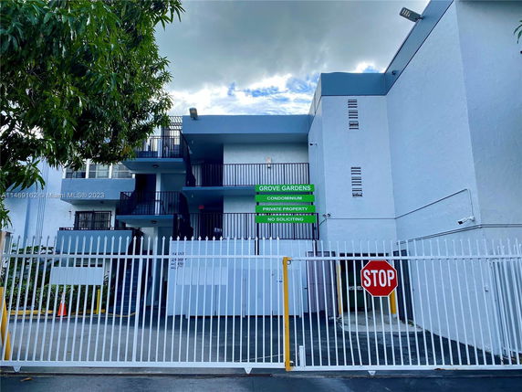 Front view of a multi-story condominium building with a security gate.