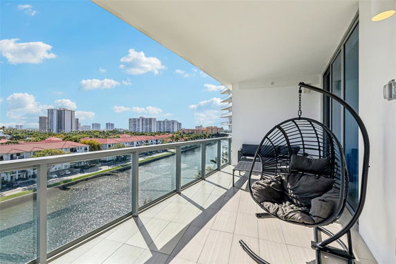 Balcony with seating overlooking a river and cityscape.