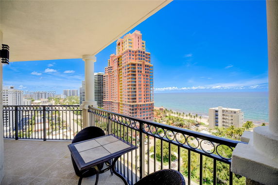 Balcony view overlooking a coastal cityscape with high-rise buildings and the ocean in the background.