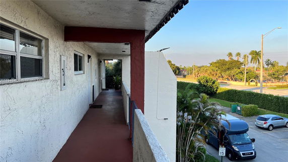 View from a balcony showing a parking area and surrounding greenery.