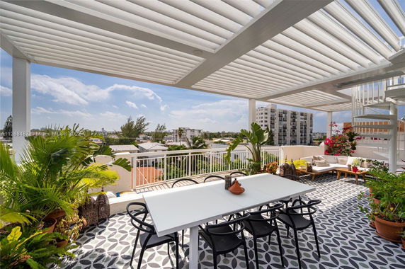 Rooftop terrace with seating area, dining table, and decorative plants.