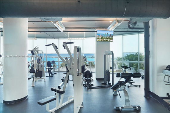 Indoor gym with exercise equipment and large windows overlooking a scenic view.