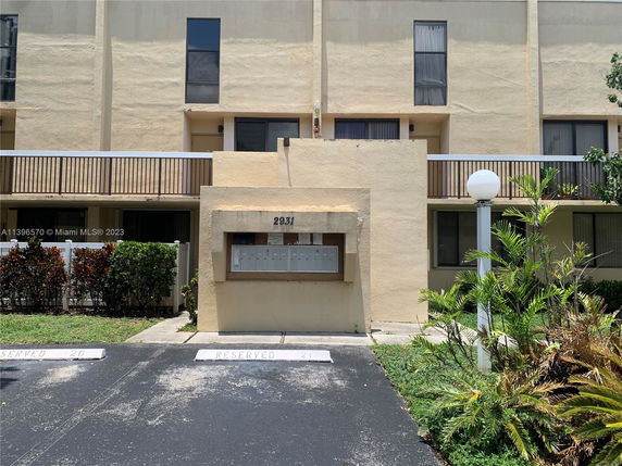Front view of a multi-story building with reserved parking spaces.