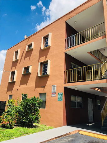 Front view of a multi-story building with balconies and several windows.