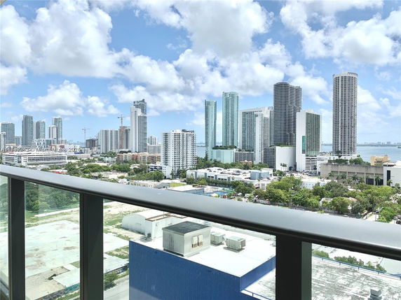 Panoramic cityscape view with high-rise buildings seen from a balcony or rooftop.