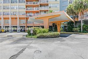 Outdoor parking area in front of a multi-story building with an awning.
