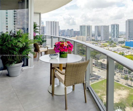 Balcony with chairs and table overlooking a cityscape.