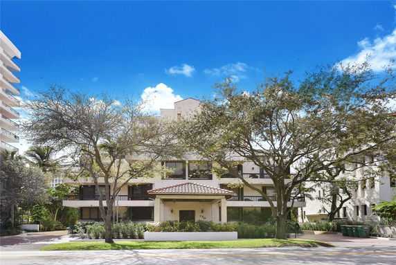 Front view of a multi-story building with balconies and a tiled entrance roof.