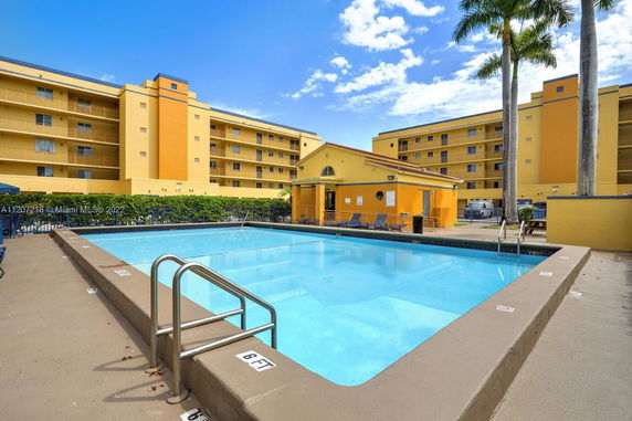 Swimming pool area in front of a multi-story residential building.