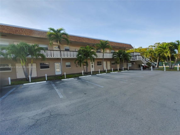 Front view of a two-story building with balconies and parking area.