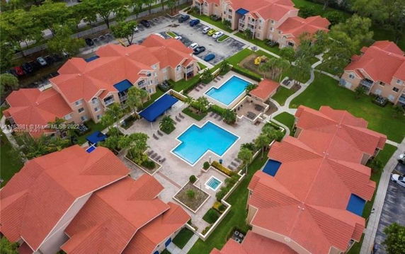 Aerial view of a residential complex with multiple buildings and a large swimming pool area.