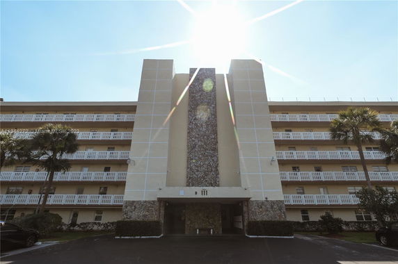 Front view of a multi-story building with balconies and a central stone facade.
