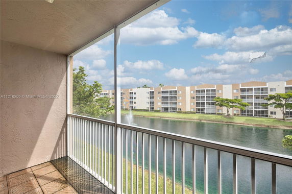 Balcony view overlooking a pond with residential buildings in the distance.